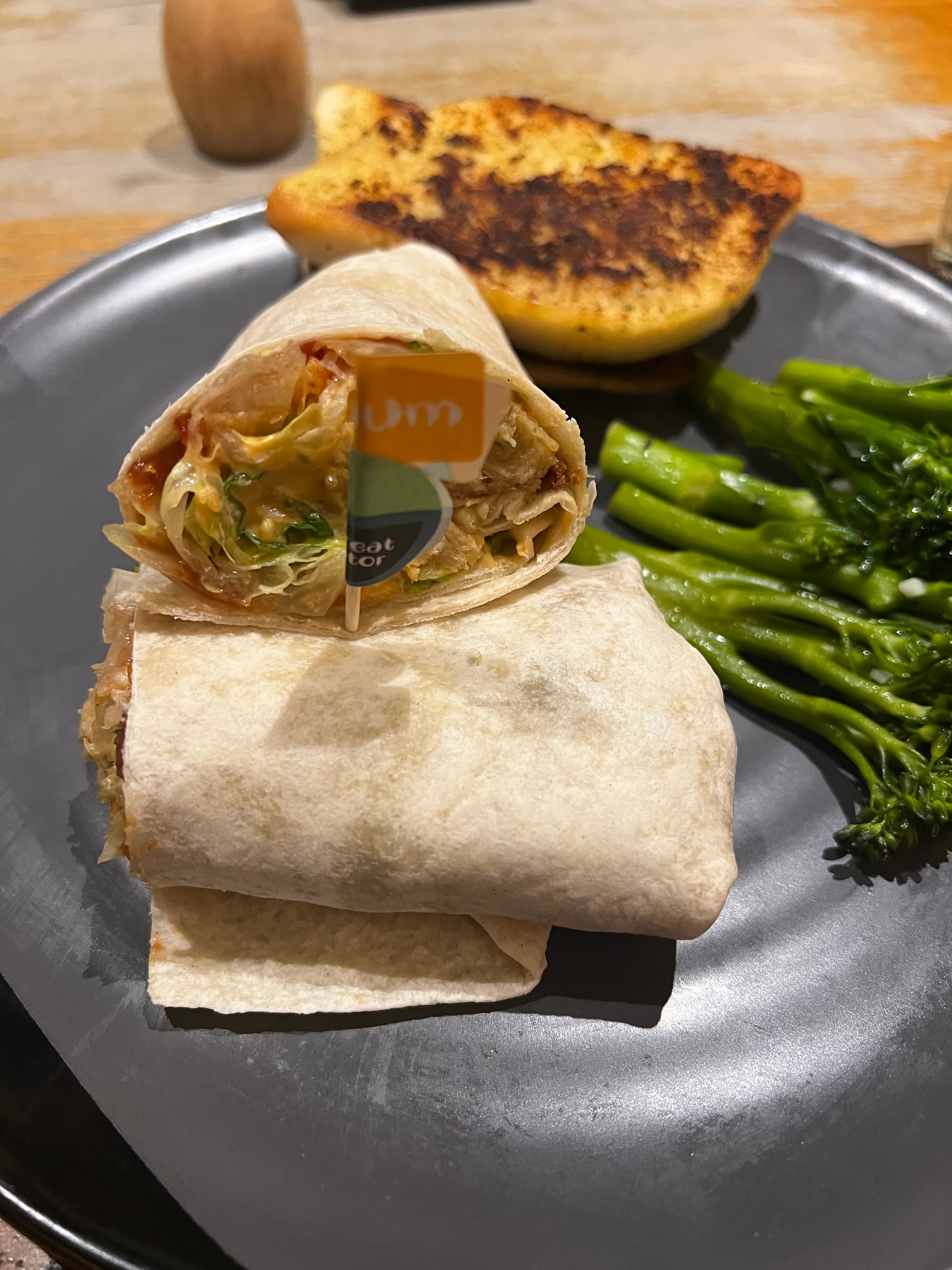 A plate of Nando's food: the Great Imitator wrap, broccoli, and garlic bread.
