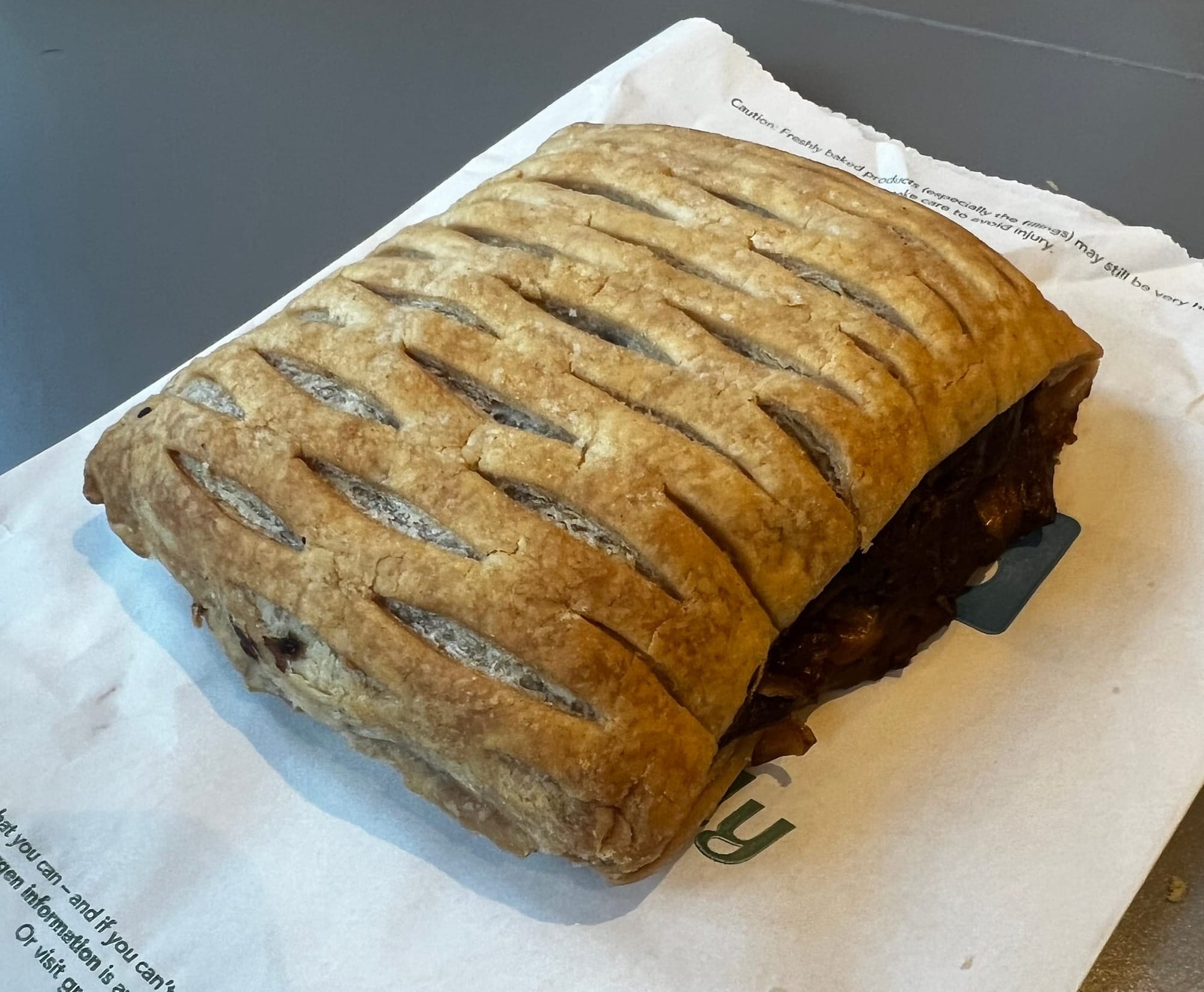 A vegan steak bake with bit of the filling spilling out of the long side.