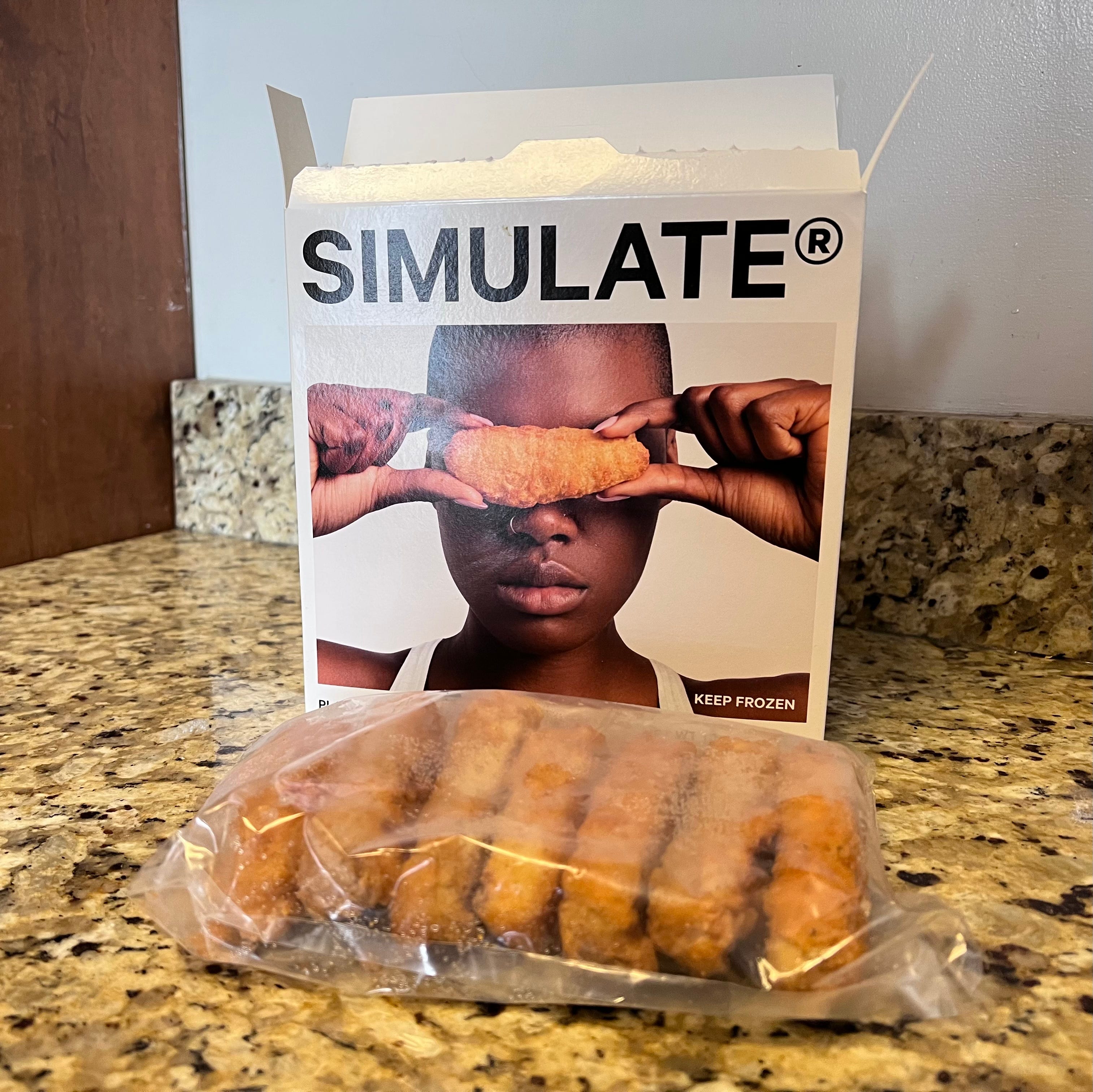 An open box of Simulate Tenders and a plastic bag with seven Tenders in front of it on a kitchen counter.