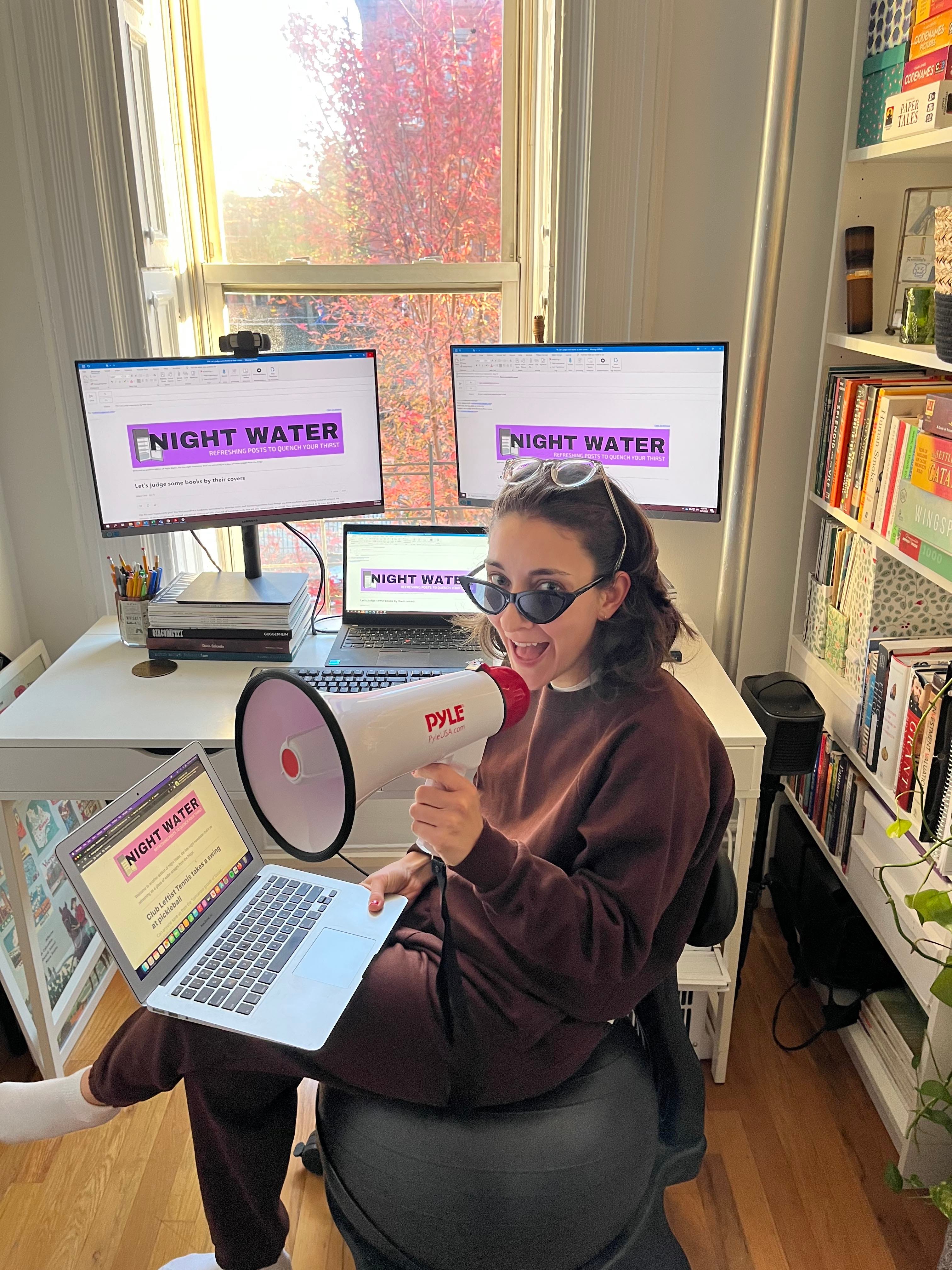 Woman with megaphone reading Night Water on four computers.