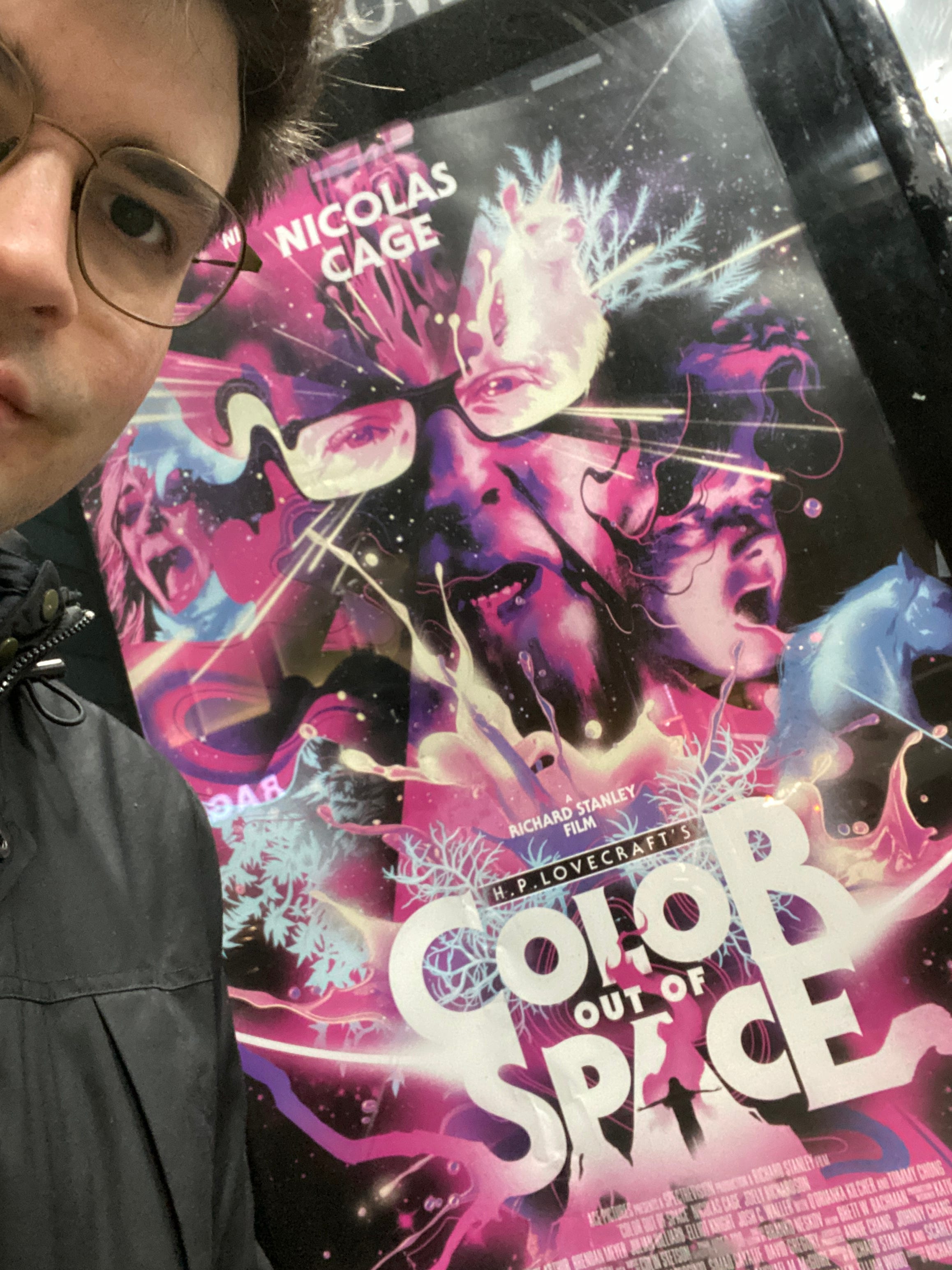 A selfie of the author, a young man with glasses, with the film poster for Color out of Space.