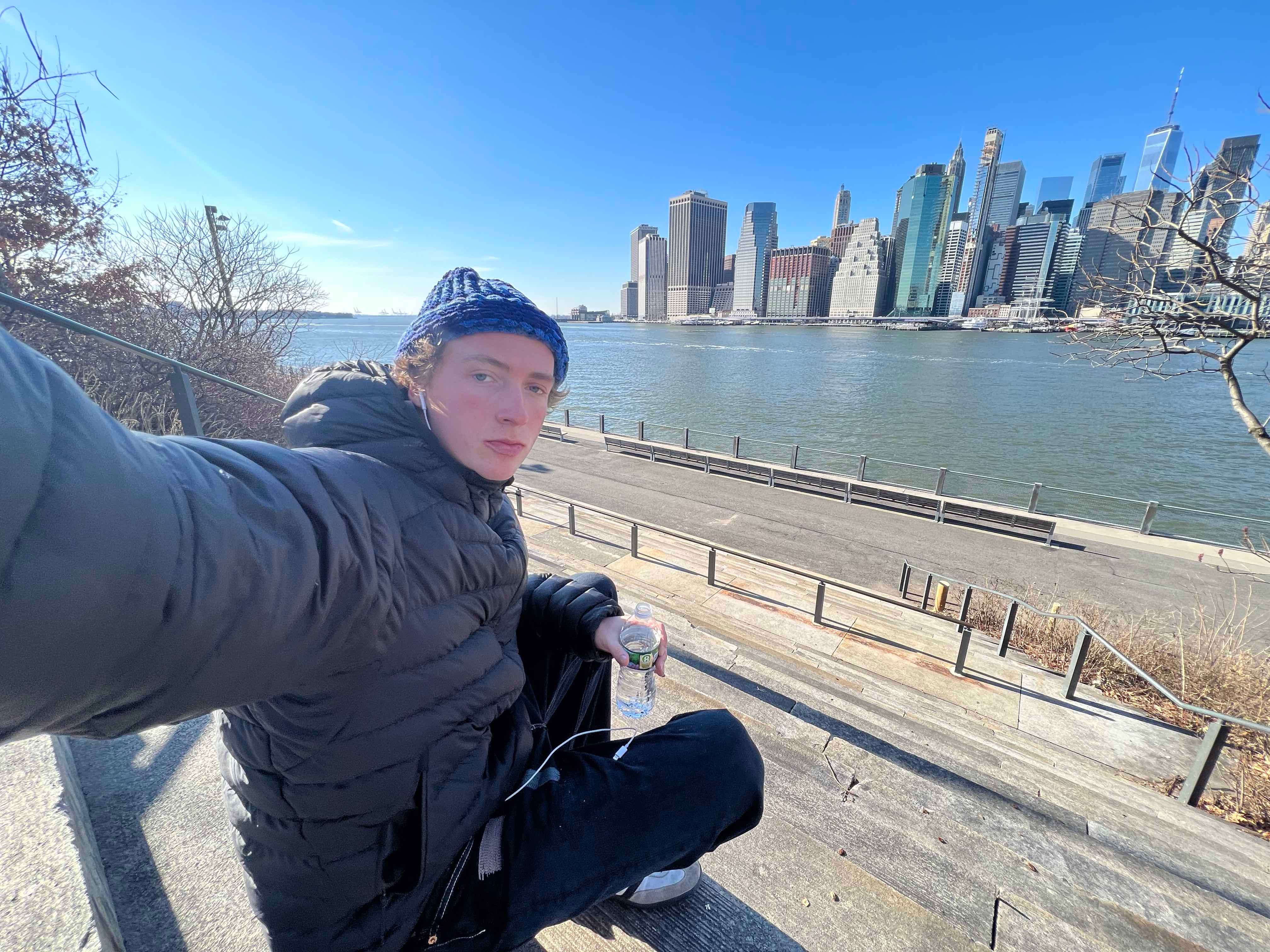A young man takes a selfie across the water from Manhattan island.
