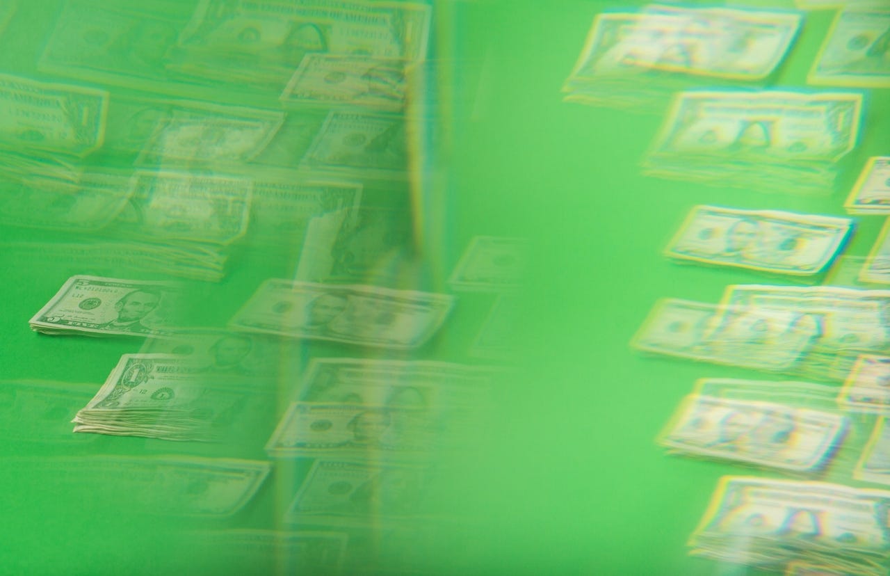 Stacks of money fading in and out of a green background.