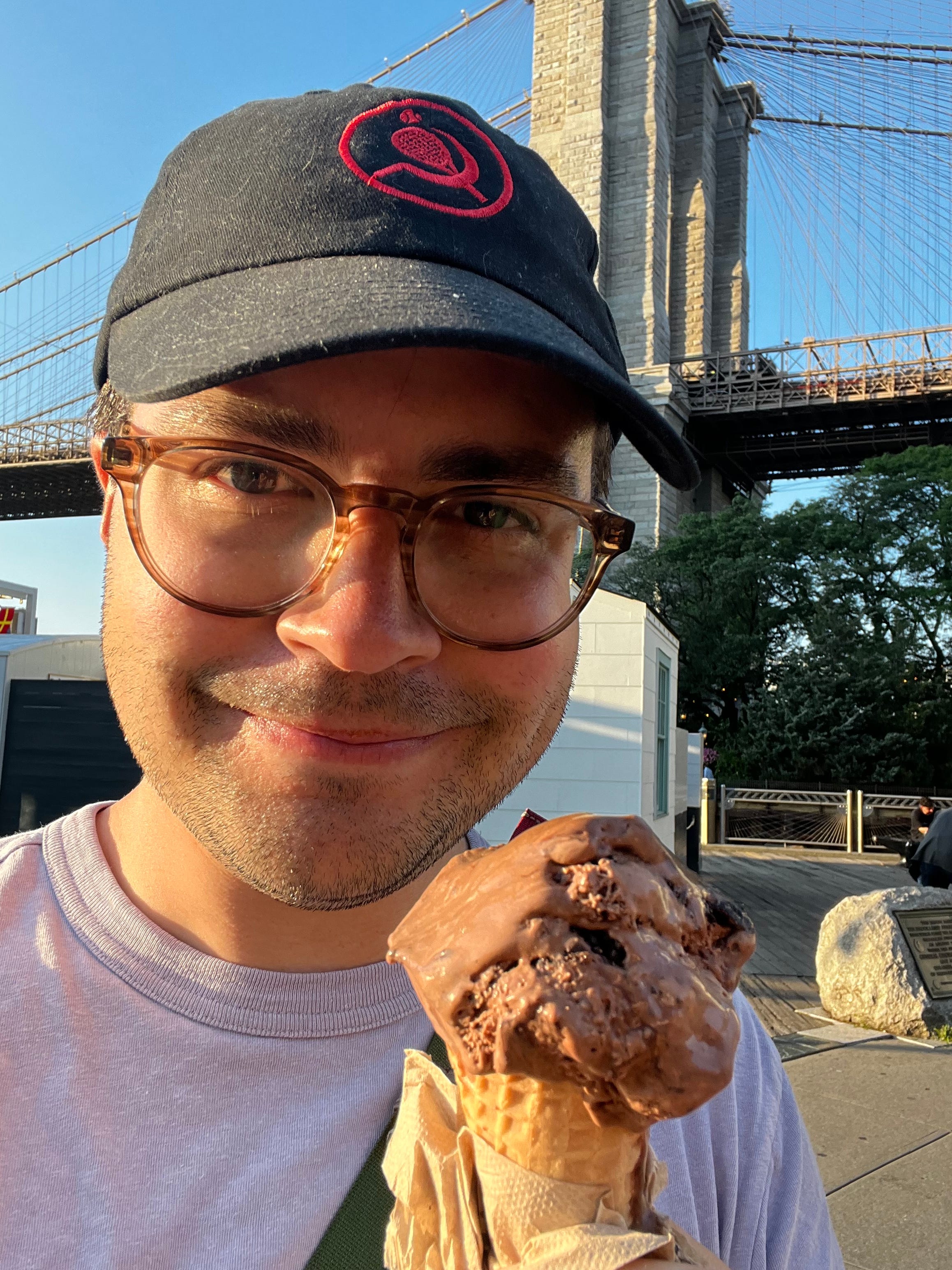 Author holding ice cream cone in front of bridge.