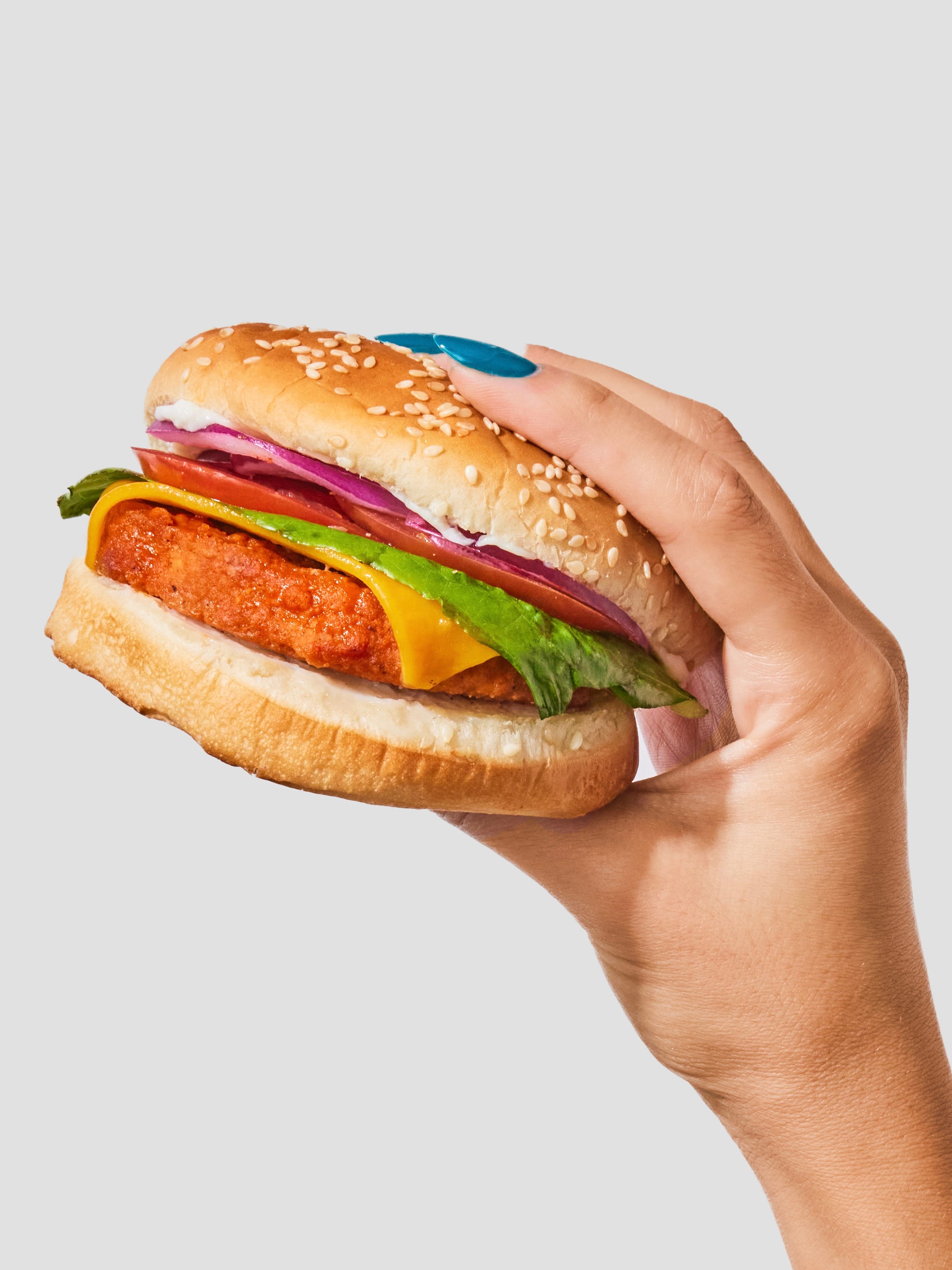 A hand holds up a buffalo chicken sandwich.