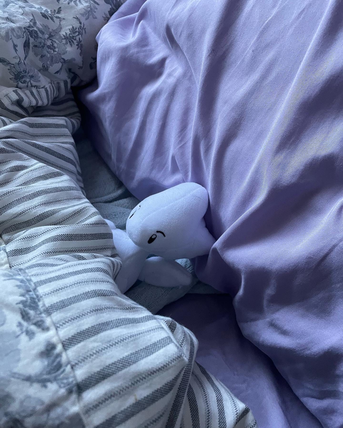 A Togetic stuffed animal, tucked in bed.