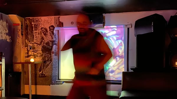 A blurry man dances in a bar.