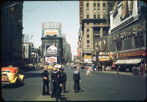 A group of sailors crosses the street at Times Square.