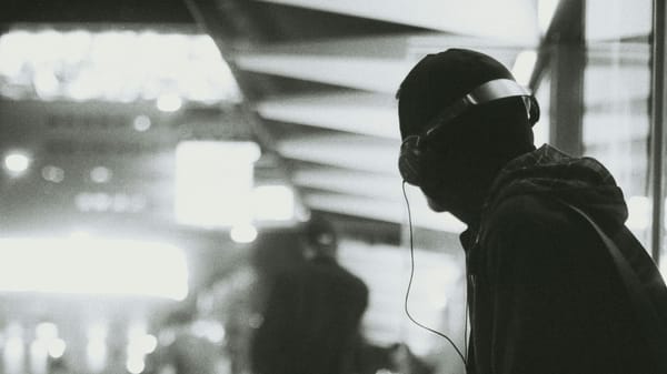 A man sits in a train station with headphones.